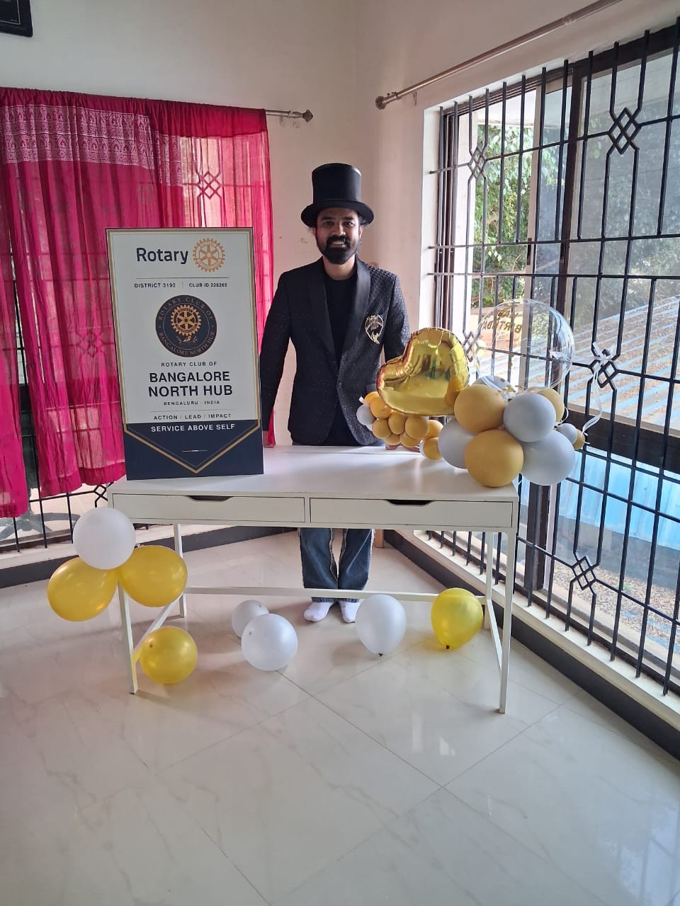 A performer beside the Rotary Bangalore North Hub banner and balloons